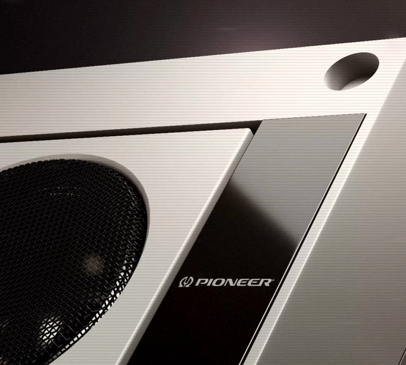 Close-up of a Pioneer audio component or speaker enclosure with brushed silver metal panels, a black mesh grille, and a glossy black accent panel featuring the white Pioneer logo.